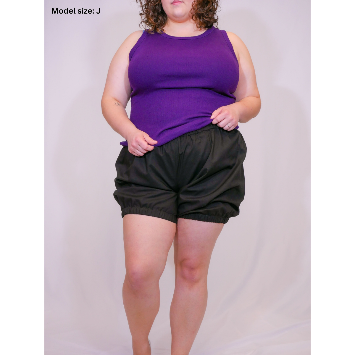 A photo of a woman in black short bloomers (size J) with a purple tank top.