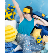 Photo of male model, matthew_aizel, wearing a sewing-themed pair of Pajama Pants and a teal crop top. He is stretching among a corner of cushions. The image elicits a feeling of sleepiness.
