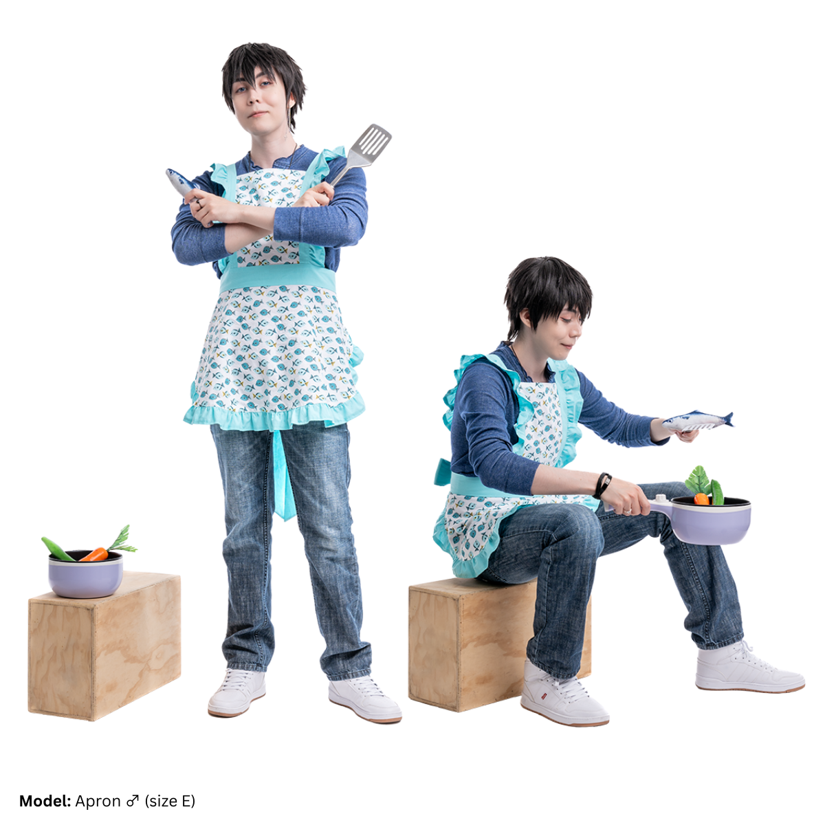 Male model, matthew_aizel, in various poses while wearing a fish-print version the Apron (men's) over a long sleeve shirt and jeans. In one variation, his arms are crossed with a fish figurine and spatula in each hand. In the other variation, he is sitting on a wooden crate and holding a pot with vegetables inside.