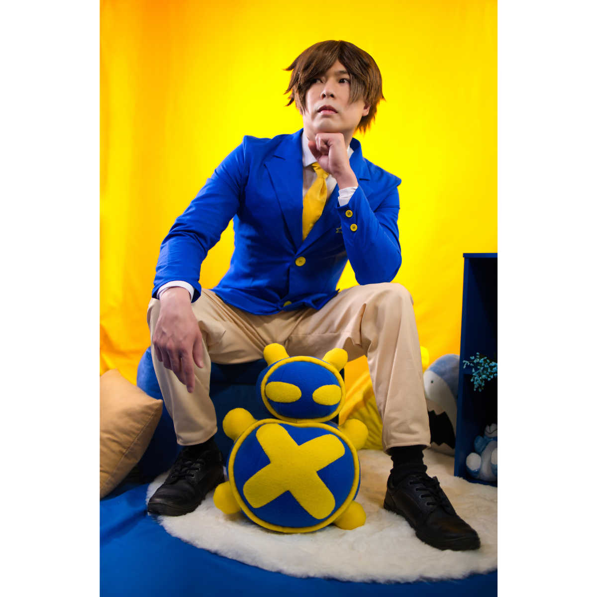 Male model (size E) sitting on a stool and posing in the Pants (men's) and blazer.
