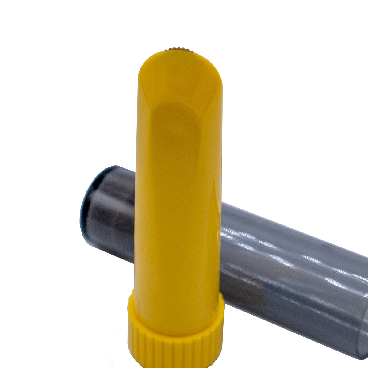 The yellow chalk wheel liner positioned upright outside of its packaging. The cap is resting horizontally behind it.