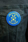 Circle Stitch Logo Button being worn on the chest pocket of a dark blue denim jacket.