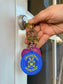 Close-up of Circle Stitch Logo keychain being displayed at the end of a set of keys while the owner is unlocking a door.