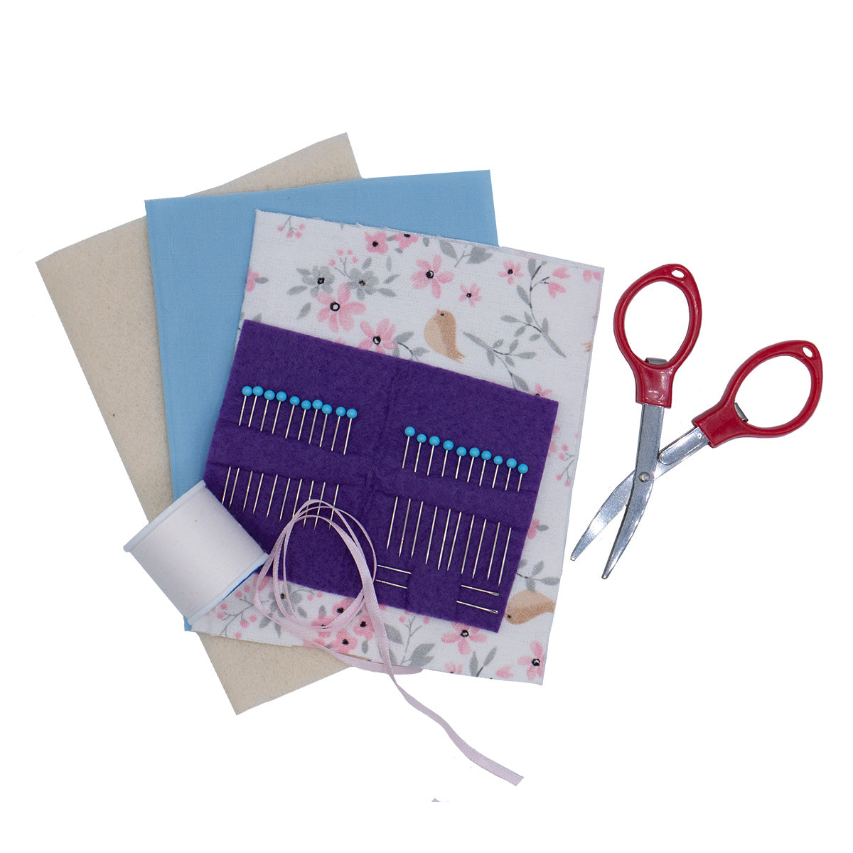 Needle Book Kit contents next to a pair of red collapsible scissors. The Needle Book kit includes fabric, glass pins in felt, a spool of thread, and ribbon.